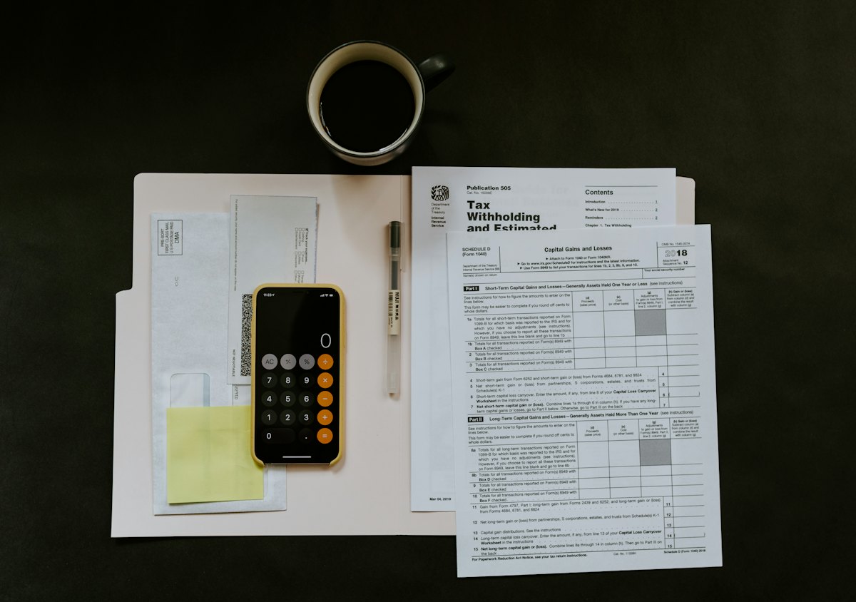 Tax paperwork, a pen and a phone on a white folder