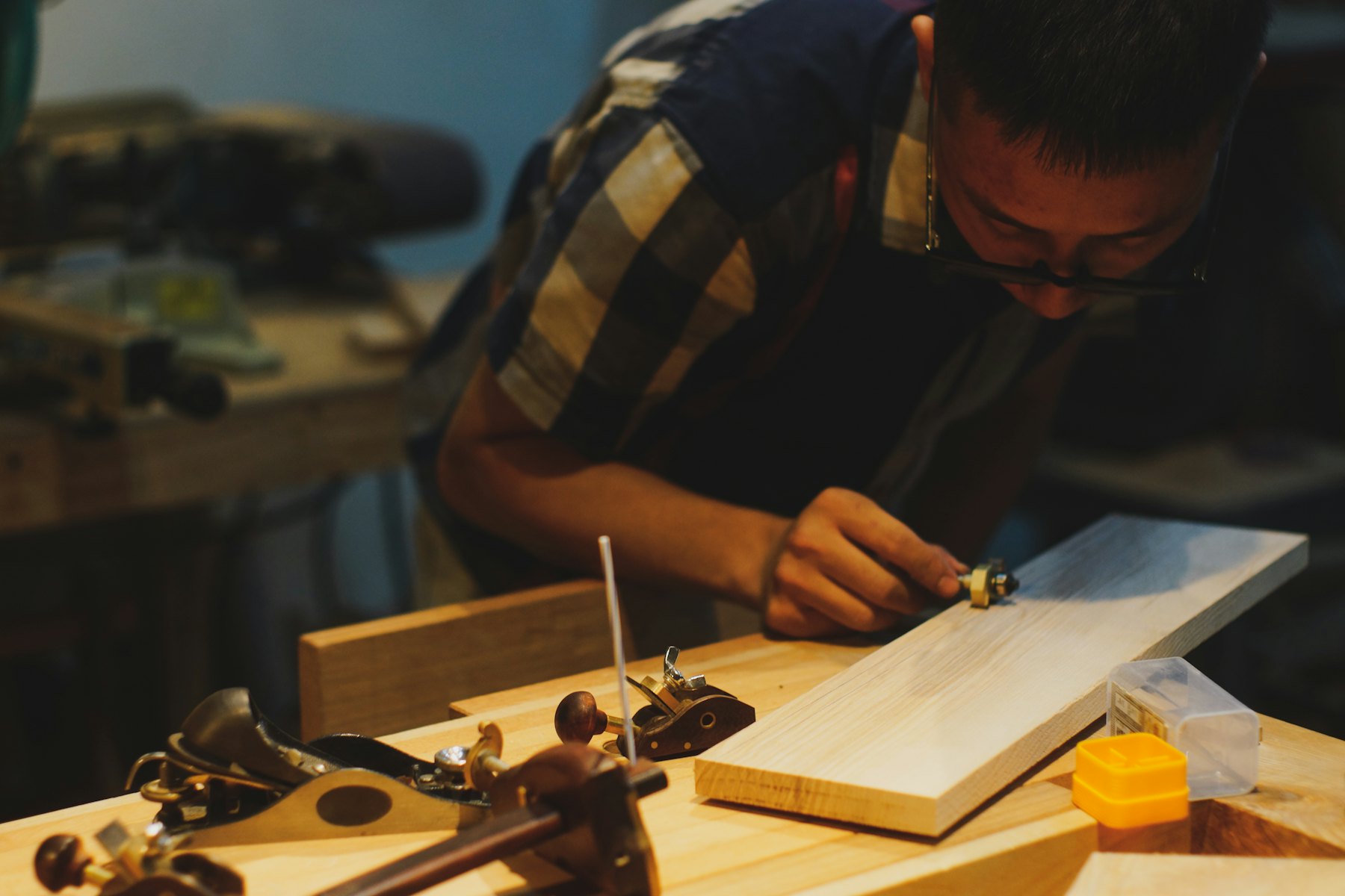 Carpenter working on timber with hand tools at a workshop bench