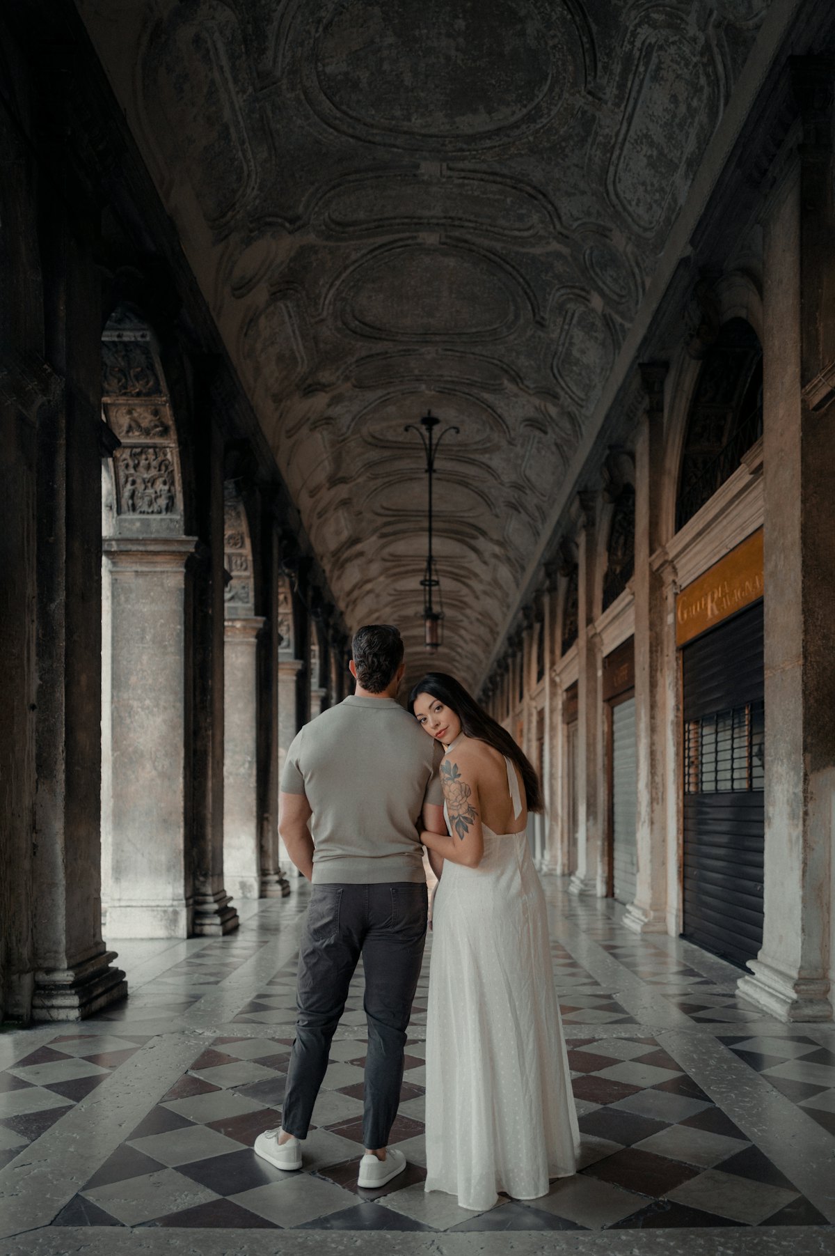 Couple walking down a grand arched hallway